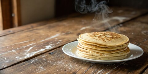 Poster - A stack of freshly cooked golden brown pancakes on a white plate, emitting warm steam and resting on a rustic wooden table surface.