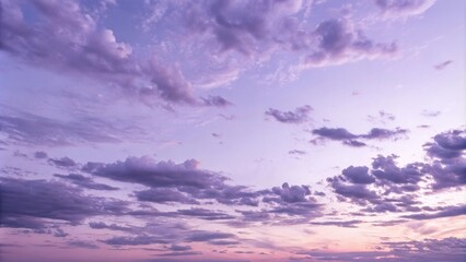 Poster - A panoramic view of the sky with a soft, ethereal glow cast by the setting sun, illuminating the fluffy, pastel-colored clouds with a delicate warmth.