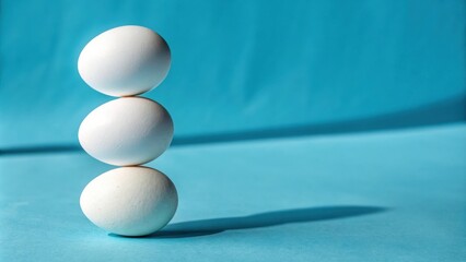 Poster - A trio of white eggs balanced precariously atop one another against a vibrant blue backdrop