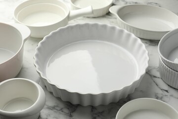 Different casseroles on white marble table, closeup