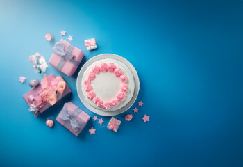 Aufkleber - A white cake with pink frosting sits on a white plate surrounded by pink and white presents and decorative accents on a blue background.