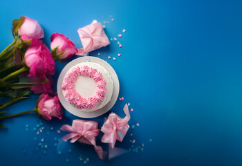 Aufkleber - A single-tiered white cake with pink frosting sits on a white plate surrounded by pink roses, pink presents, and pink sprinkles on a blue background.
