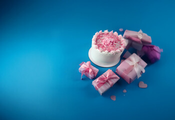Aufkleber - A white cake with pink frosting and sprinkles sits on a blue background surrounded by pink wrapped gifts.