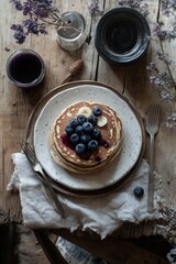 Poster - Stacked pancakes with blueberries, bananas and purple syrup on a wooden table.