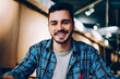 © BullRun - Portrait of cheerful male student enjoying learning in coworking office using laptop computer for research,happy freelancer looking at camera during making project for remote job making notes