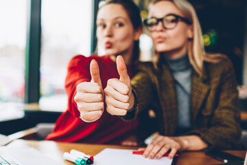 Fototapete - Selective focus on sign likes of two successful female students wich looking at camera.Blurred background with happy best friends showing thumb up working together at laptop computer in university