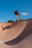 young skater wearing black tshirt skating inside a bowl in a skate park. 