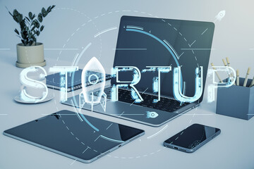 Poster - Startup hologram overlay on office desk with tech devices and laptop background.