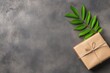 © Thanyarat - A creatively wrapped eco-friendly gift with recyclable paper and a sprig of fresh greenery tied with twine, placed on a neutral-toned surface