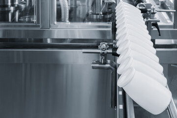 Poster - A row of white bottles are lined up on a conveyor belt. The bottles are all the same size and shape