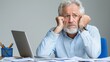 © kinara art design - Worried senior man sitting at desk with paperwork and laptop.