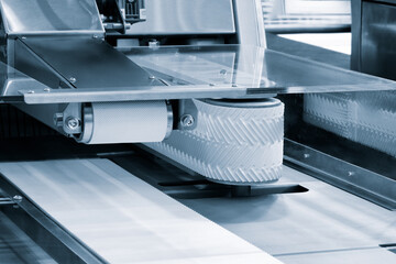Poster - A conveyor belt is moving a white object. The belt is made of rubber and is moving the object from one place to another. The object is likely a product that is being manufactured or processed
