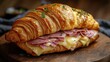 © Vadym - Delicious ham, Swiss cheese croissant sandwich on wooden plate. Fresh, appetizing breakfast lunch option. Buttery croissant stuffed with layers of flavorful ham, melted Swiss cheese. Perfect for