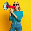 © AIrina - Trendy young woman in sunglasses holding a megaphone, making a bold statement on International Women's Day