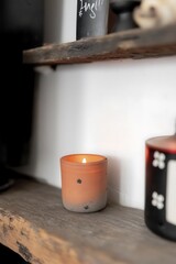 Canvas Print - A lit candle on a wooden shelf, creating a cozy atmosphere.