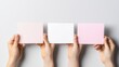 © kinara art design - Three hands hold blank pastel cards against a gray background.