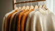 © Atmospheric stock - Cozy knitted sweaters on wooden hangers in warm earth tones