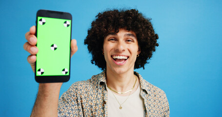 Poster - Happy man, portrait or phone with green screen for advertising or online marketing on a blue studio background. Male person, user or model with smile or mobile smartphone display for new software app