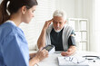 © New Africa - Doctor measuring patient's blood pressure at table indoors