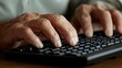 © Munlika - A close-up of a man typing on a keyboard, showing his hands in motion, illustrating a busy work environment or digital project.