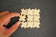 © Fauzi - The puzzles are arranged and the hand holds the last puzzle for combination. concept of solution or complete task. teamwork and cooperation concept. Hand to complete last piece wood puzzle.