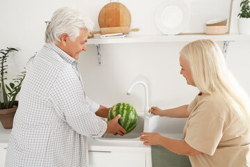 Sticker - Mature couple washing fresh watermelon in kitchen