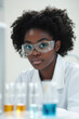 © Steven - Young Black female scientist in a laboratory setting, wearing safety goggles and a lab coat, surrounded by colorful chemical solutions in test tubes.