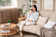 © Pixel-Shot - Young pregnant woman talking by mobile phone on sofa at home
