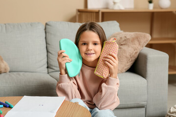 Wall Mural - Cute little happy girl with pencil cases, notebook and markers sitting at home