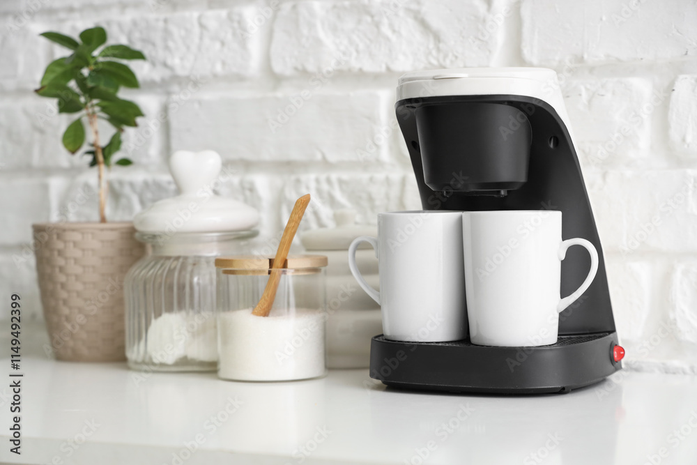 Coffee machine with cups, sugar and plant on shelf near white brick wall