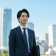 © honami - Young Japanese Businessman in Formal Suit Holding Briefcase in Modern Cityscape