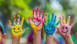 © CreativeInside - A group of hands with colorful paint on them, each hand holding up their palm and smiling face painted in the middle of it.