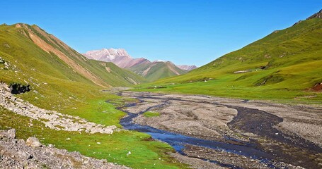 Wall Mural - Curved river and green grassland with mountain natural landscape in summer. Beautiful scenery along the Duku Highway in Xinjiang, China.