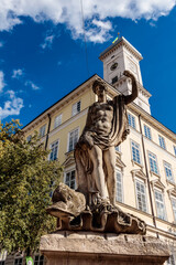 Wall Mural - A statue of a man holding a shield is on a stone pedestal in front of a building