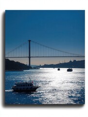 Poster - Bosphorus Strait, with boats sailing under the Istanbul Bridge. The bridge creates a striking silhouette against the bright blue sky and calm waters,