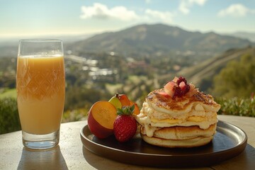 Wall Mural - Delicious pancakes with fresh fruit and juice, enjoyed outdoors with a scenic mountain view.