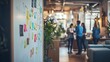 © Dinara - A close-up shot of a whiteboard covered in colorful sticky notes, with a blurred background of people in a modern office.