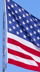 Wall Mural - us flag on a flagpole blowing in the breeze. vertical video.