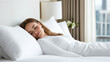 © Aris - Australian woman sleeping comfortably on white bed in luxury hotel