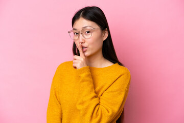 Wall Mural - Young Chinese woman isolated on pink background With glasses and doing silence gesture