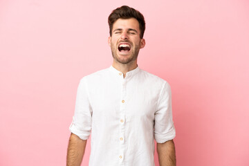 Wall Mural - Young caucasian handsome man isolated on pink background shouting to the front with mouth wide open