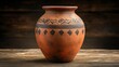 © irawan710 - Rustic terracotta vase with tribal design on a wooden table.