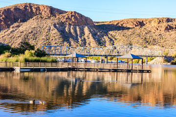 Wall Mural - A bridge spans a body of water with a view of mountains in the background