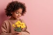 © c80 - Child holding a bouquet of bright yellow flowers against a pink background with a gentle expression