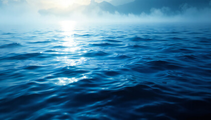 Wall Mural - Calm blue water surface with gentle waves reflecting light , surrounded by misty mountains in the background.