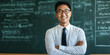 © LK  - A smiling Asian male teacher in a classroom with a blackboard in the background. Teacher concept.