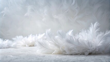 Wall Mural - Soft white feathers arranged on a neutral surface with a blurred background of more feathers.