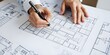 © Redhill - architect working on project. An architect's hand meticulously draws a building plan with a pen, capturing the essence of architectural planning and design, emphasizing precision and creativity