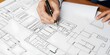 © Redhill - architect working on project. An architect's hand meticulously draws a building plan with a pen, capturing the essence of architectural planning and design, emphasizing precision and creativity
