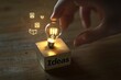 © Sean Hoong - A hand touching a glowing light bulb, placed on a smooth wooden block with 'Ideas' inscribed in a sleek, modern font, with floating digital elements symbolizing innovation.